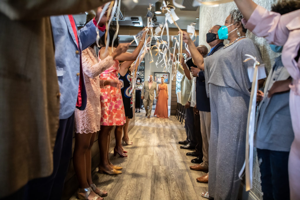 Intimate wedding dinner reception. Guests are lined up on either side of the hallway with celebration wands.
How to have a Covid friendly event.